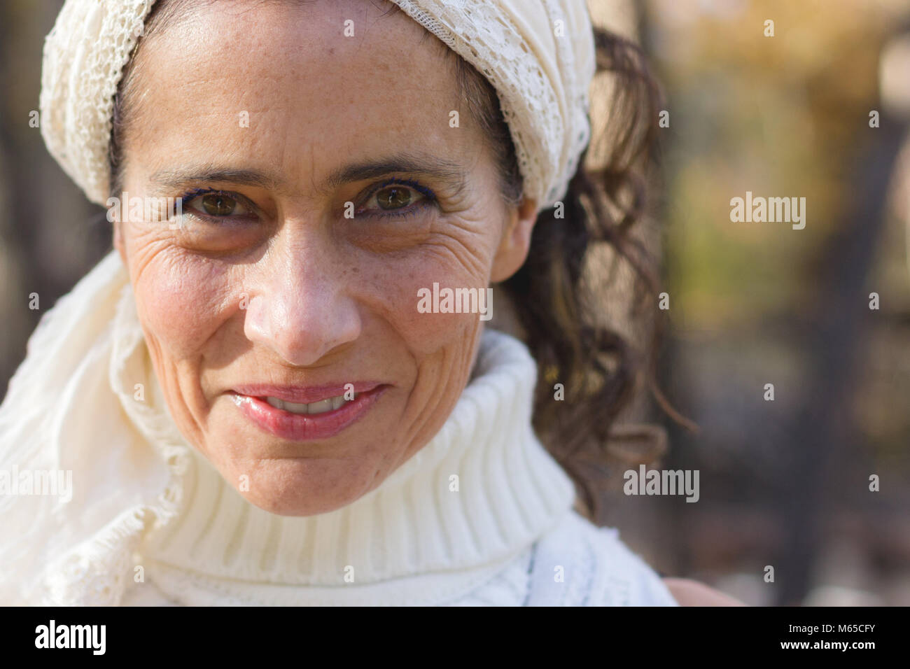 Close up on confiant mature woman smiling avec col roulé blanc chandail tricoté et châle sur tête Banque D'Images