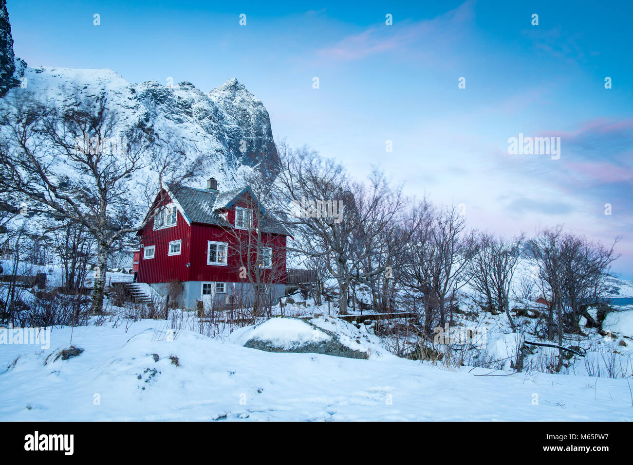 Chalet rouge dans la neige et les arbres sous pré-aube Banque D'Images