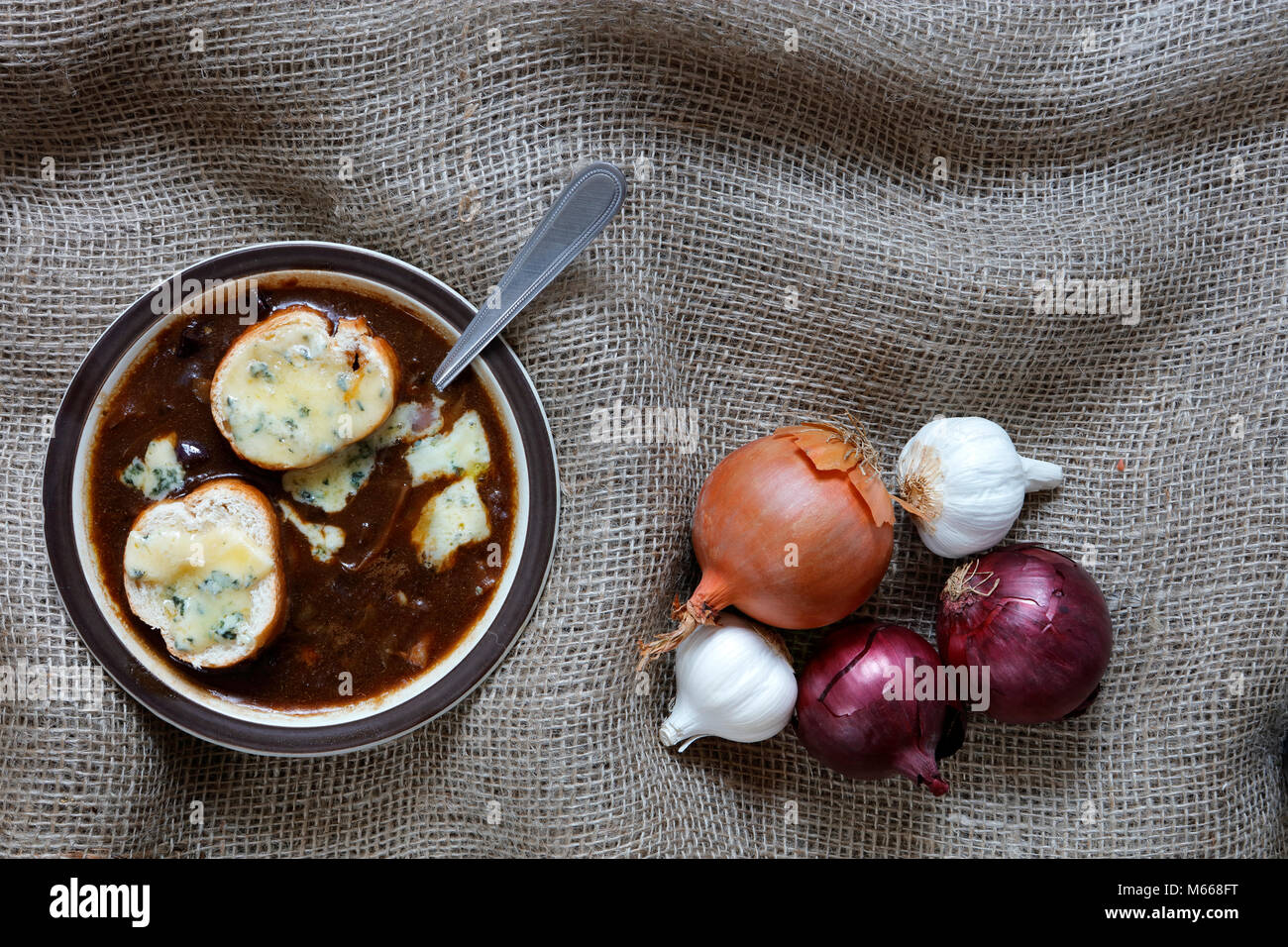 La soupe à l'oignon avec blue stilton fromage gruyère à l'ail, les échalotes et le français Echalion rouge et faire revenir les oignons dans un panier en osier sur une toile de jute backg Banque D'Images
