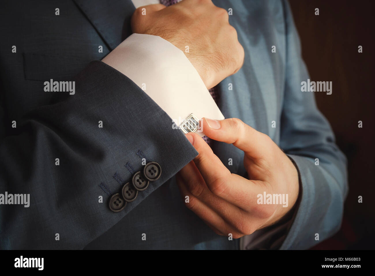 Groom mettant sur boutons de manchettes qu'il s'habille en tenue de cérémonie close up Banque D'Images