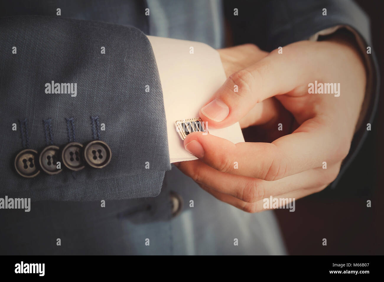 Groom mettant sur boutons de manchettes qu'il s'habille en tenue de cérémonie close up Banque D'Images