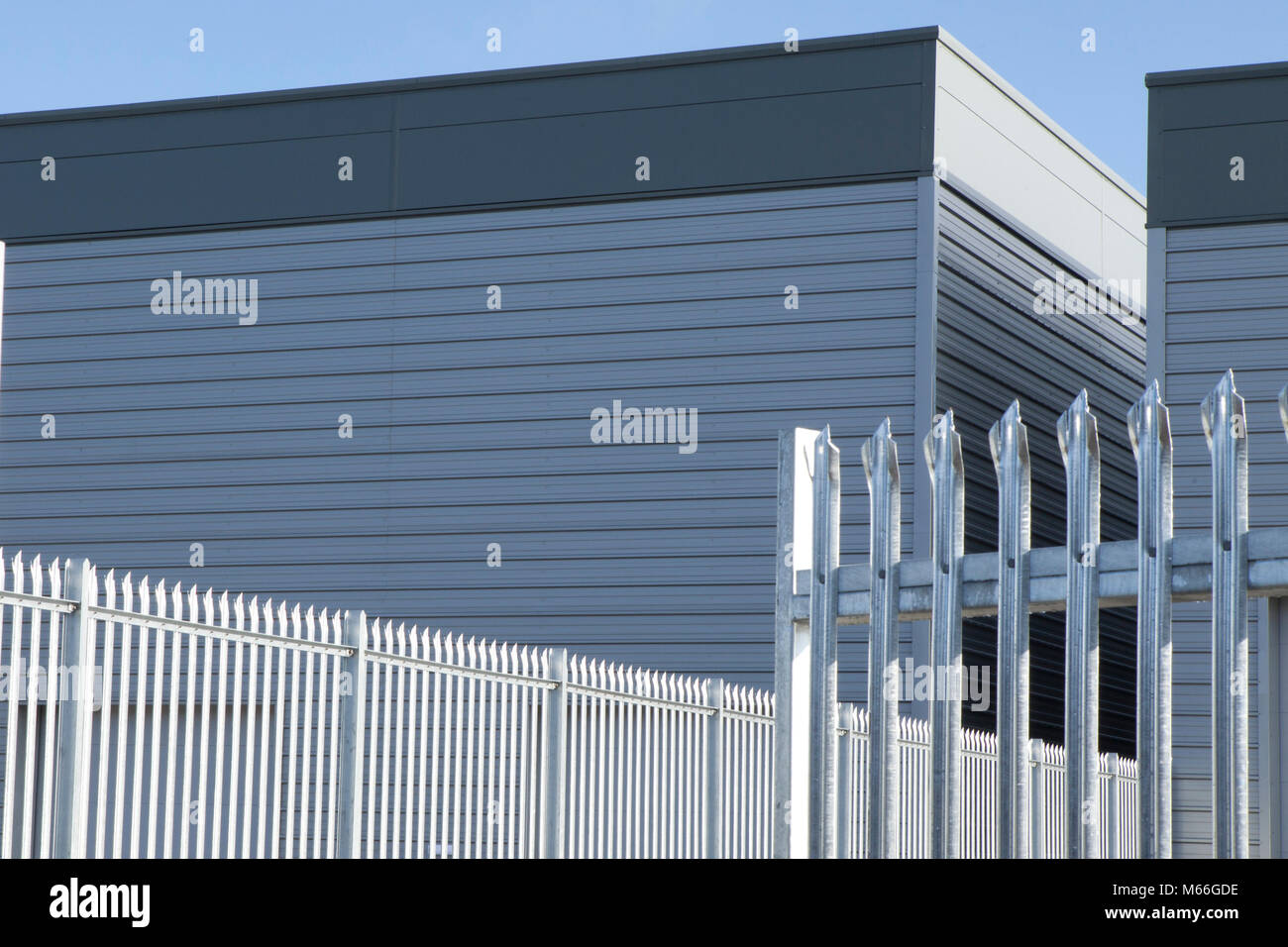 Nouveau dépôt d'entreposage et de bardage métallique de la baie de chargement et le ciel bleu du graphique, une clôture de sécurité à l'angle. Banque D'Images