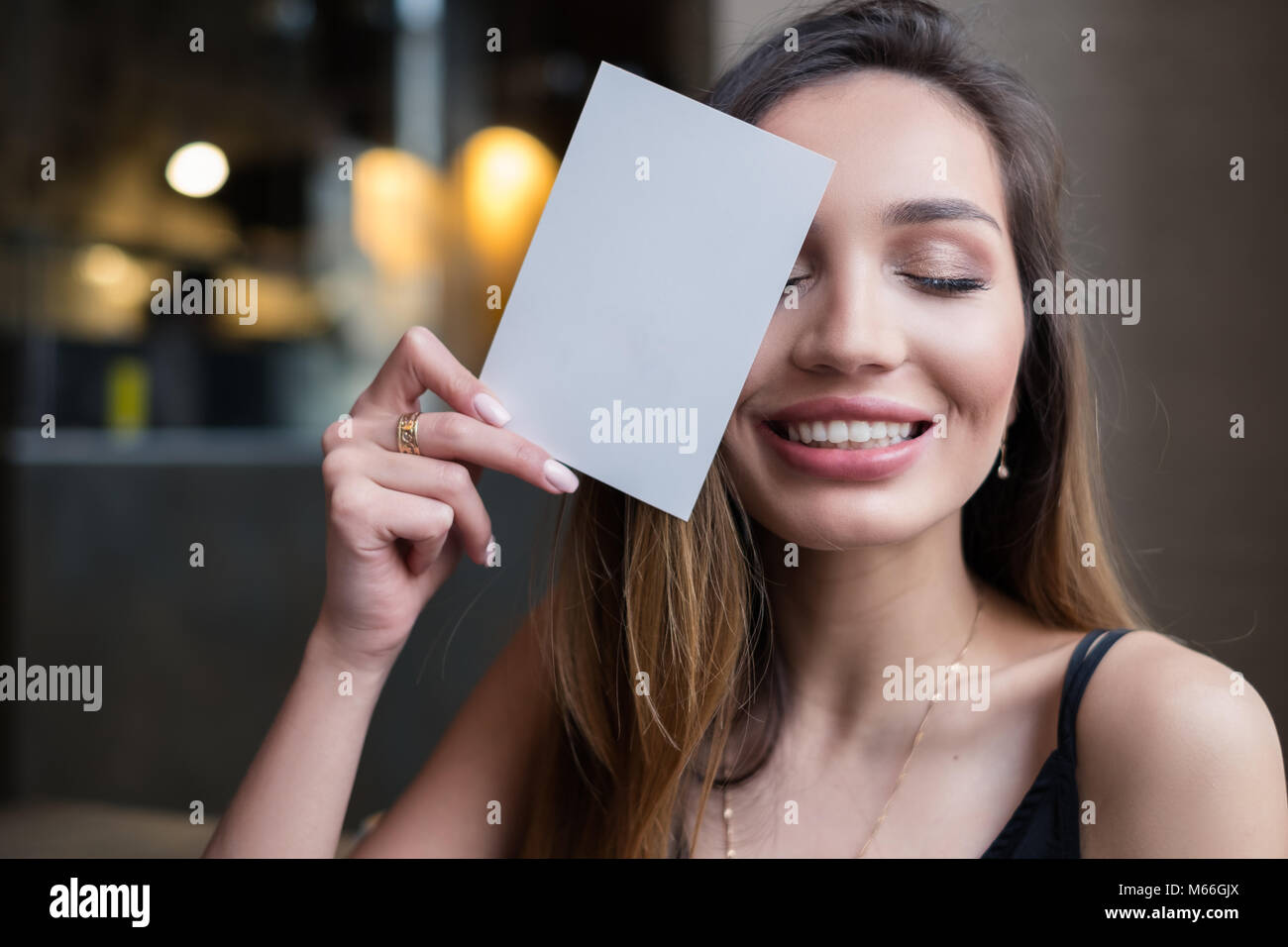 Smiling woman holding carte vierge en face de son visage Banque D'Images