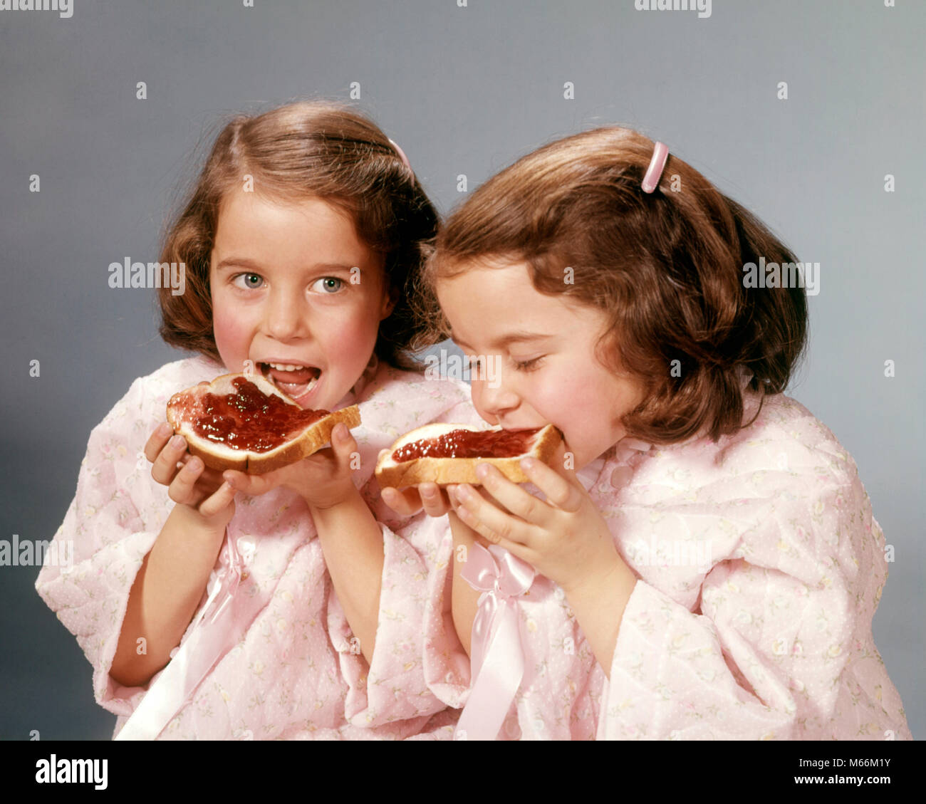 1960 TWIN FILLES BRUNETTE EATING TRANCHES DE PAIN ET CONFITURE - kf5433 HAR001 HARS MATCHING même contre-EN-CAS FAIM NOURRIR LE BONHEUR TRANCHE BÉNÉFICIANT D'UNE CROISSANCE QUI PIQUENT LES TRANCHES D'ENFANT DE NOURRITURE DE CONNEXION À L'APPARENCE DES JUVÉNILES EN DOUBLE SE RESSEMBLENT, pain et confiture Origine ethnique Caucasienne cloner l'identité génétique des gènes à l'ANCIENNE GELÉE DE PERSONNES Banque D'Images