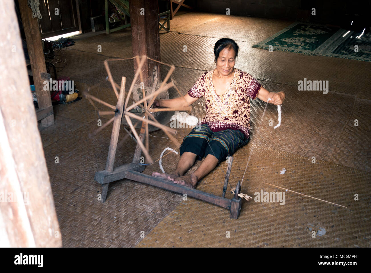 Une vieille femme ethnique filer dans un petit village tribal juste à côté de la rivière Nam Ou au Laos. Banque D'Images