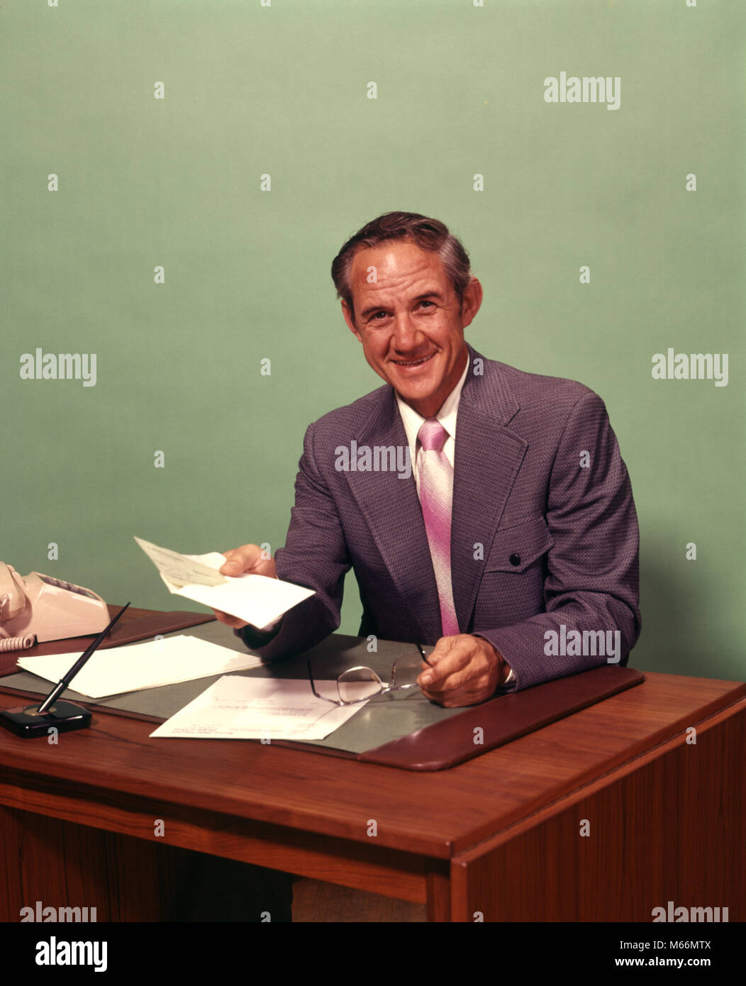 1970 middle-aged MAN SITTING AT DESK HOLDING VÉRIFIER SMILING AT CAMERA - ko630 HAR001 HARS, mi-longueur à l'intérieur d'adulte d'ÂGE MOYEN NOSTALGIE CONFIANCE HOMME D'ÂGE MOYEN LIEU DE TRAVAIL CONTACT OCULAIRE 45-50 ans 50-55 ans SUCCÈS Objectifs collier blanc costume et cravate CRAVATE COMPTE VENDRE LE BONHEUR JOYEUX SOURIRES PAIEMENT FACTURE Origine ethnique Caucasienne VENDEURS HOMMES COMMIS À LA CAMÉRA À L'ANCIENNE PROFESSION PERSONNES Banque D'Images