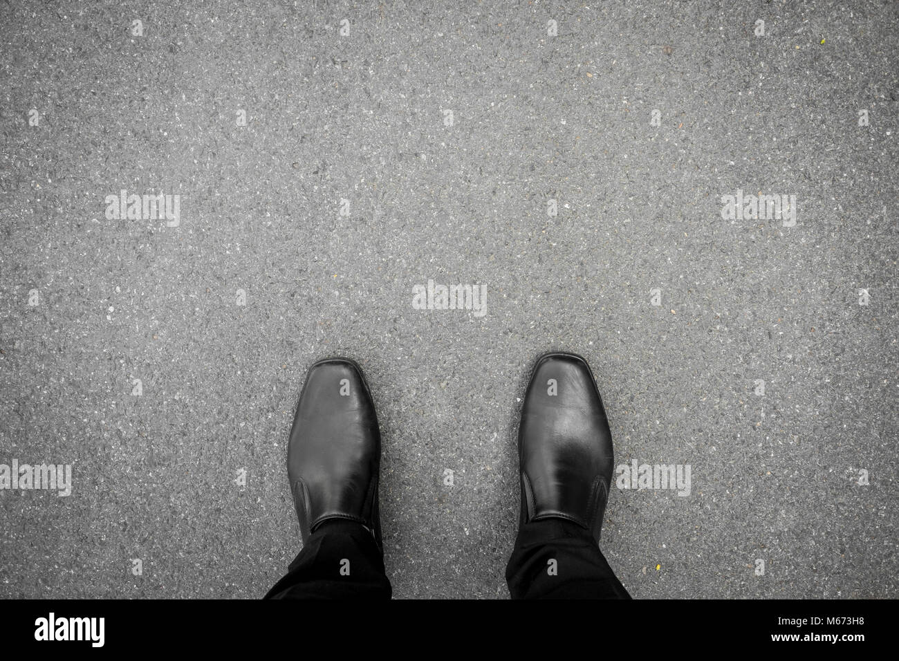 Chaussures noires debout sur le plancher de béton d'asphalte Banque D'Images