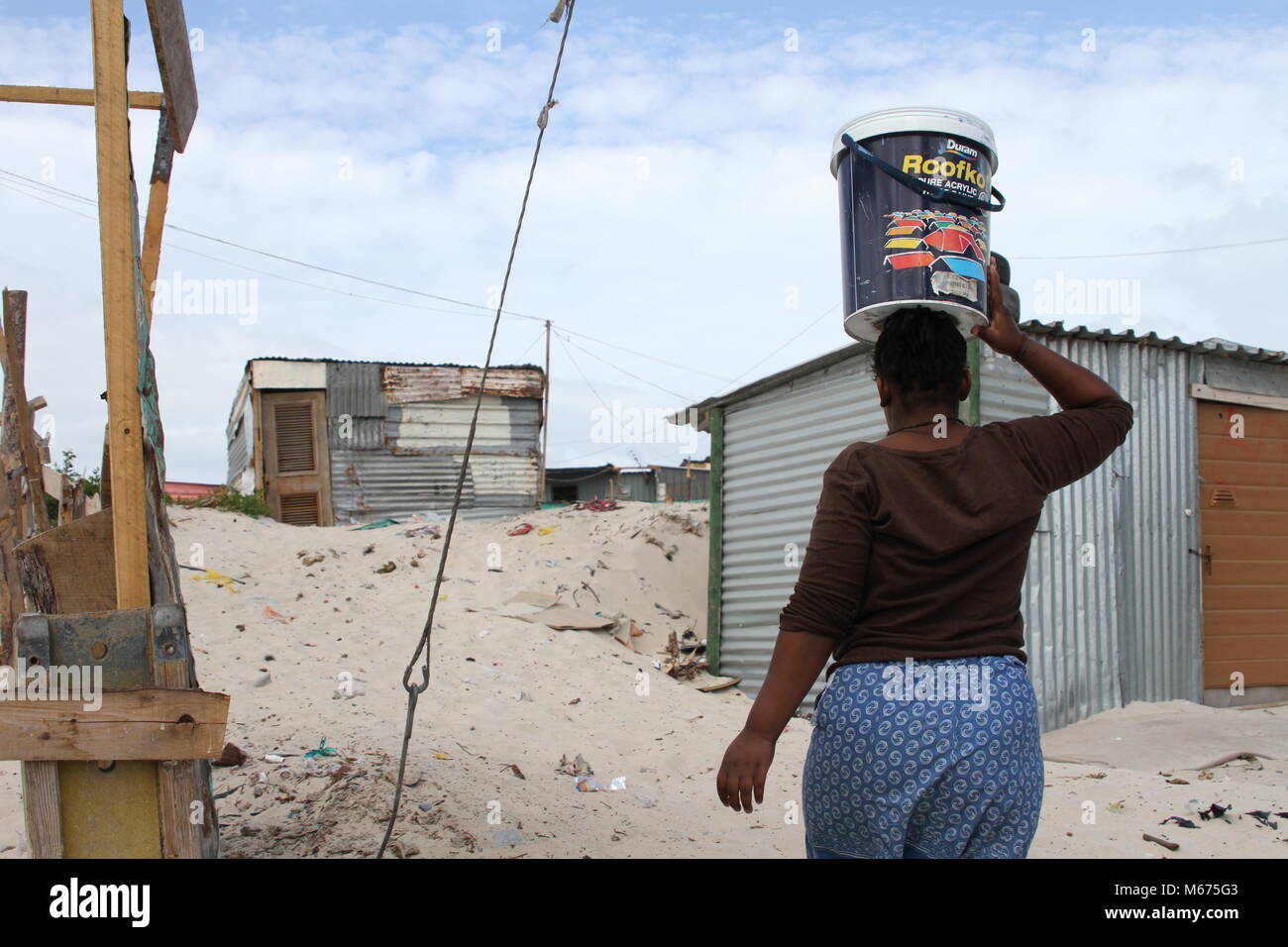09 février 2018, Afrique du Sud, Cape Town, Khayelitsha : Qosholo Mandla, 25 ans, qui vit dans le bidonville de Khayelitsha près du Cap, a pour transporter 25 litres d'un robinet commun tous les jours. Sa cabane misérable ni dispose d'une cuisine et d''une salle de bains. L'eau doit suffire pour boire, cuisiner, se laver, nettoyer et faire la lessive. Photo : Kristin Palitza/dpa Banque D'Images
