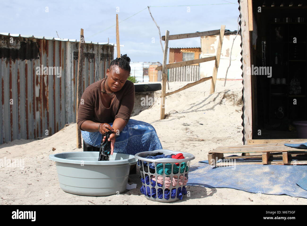 09 février 2018, Afrique du Sud, Cape Town, Khayelitsha : Qosholo Mandla, 25 ans, qui vit dans le bidonville de Khayelitsha près du Cap, a pour transporter 25 litres d'un robinet commun tous les jours. Sa cabane misérable ni dispose d'une cuisine et d''une salle de bains. L'eau doit suffire pour boire, cuisiner, se laver, nettoyer et faire la lessive. Photo : Kristin Palitza/dpa Banque D'Images