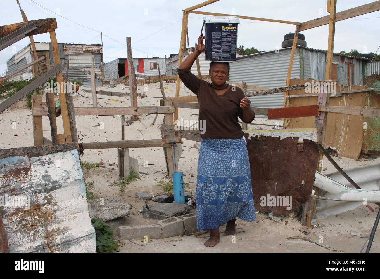 09 février 2018, Afrique du Sud, Cape Town, Khayelitsha : Qosholo Mandla, 25 ans, qui vit dans le bidonville de Khayelitsha près du Cap, a pour transporter 25 litres d'un robinet commun tous les jours. Sa cabane misérable ni dispose d'une cuisine et d''une salle de bains. L'eau doit suffire pour boire, cuisiner, se laver, nettoyer et faire la lessive. Photo : Kristin Palitza/dpa Banque D'Images