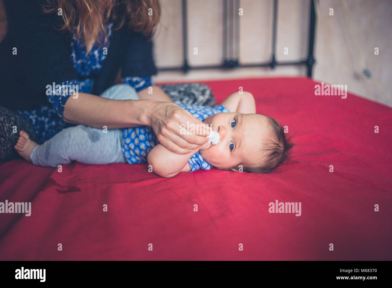 Une jeune mère est d'essuyer le nos de de son petit bébé Banque D'Images