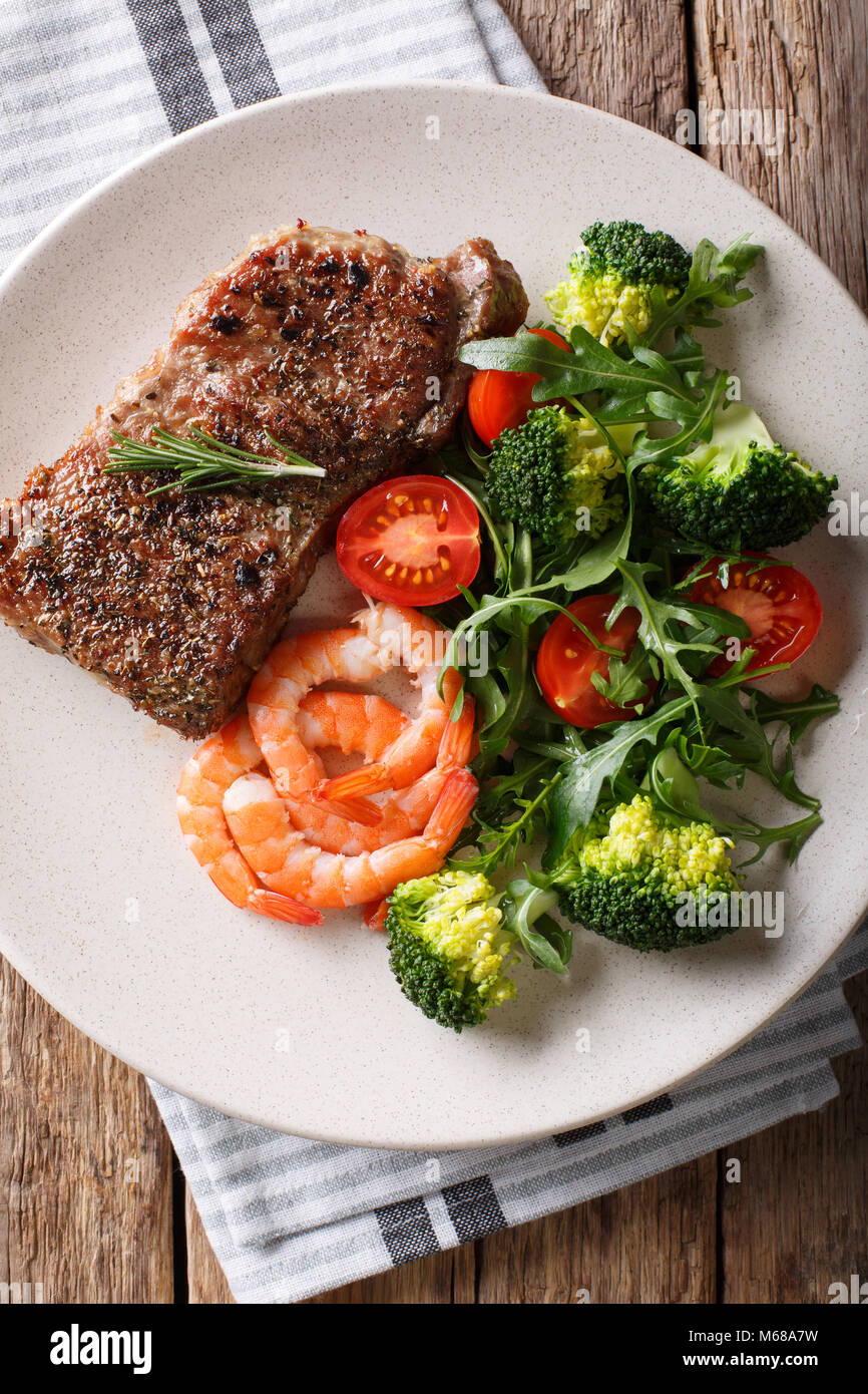 Pavé de boeuf aux gambas et brocoli, tomates, roquette libre sur la plaque sur la table. Haut Vertical Vue de dessus. Terre et mer. Banque D'Images