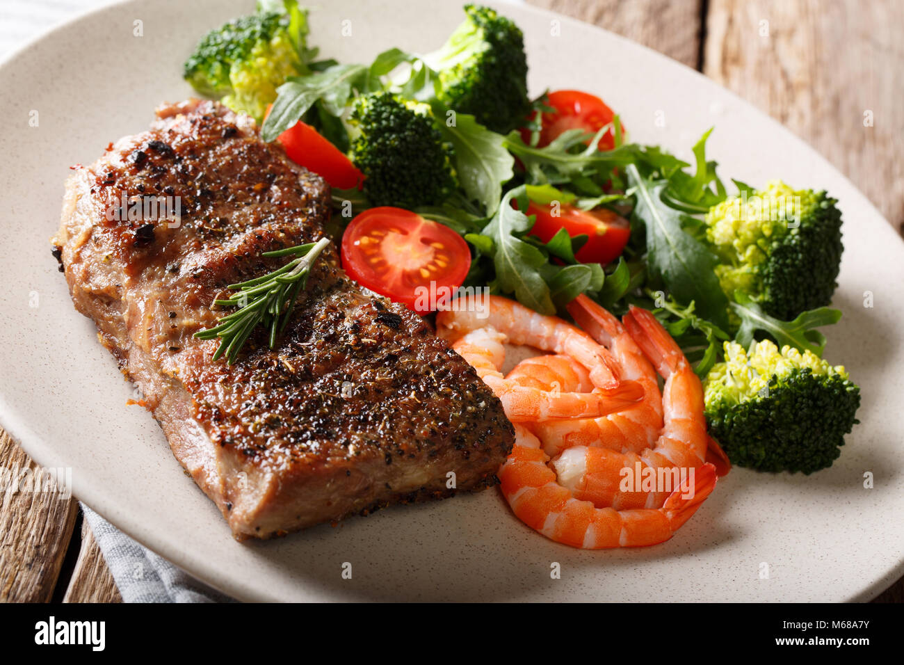 Pavé de boeuf aux gambas et brocoli, tomates, roquette libre sur la plaque sur la table. L'horizontale. Terre et mer. Banque D'Images