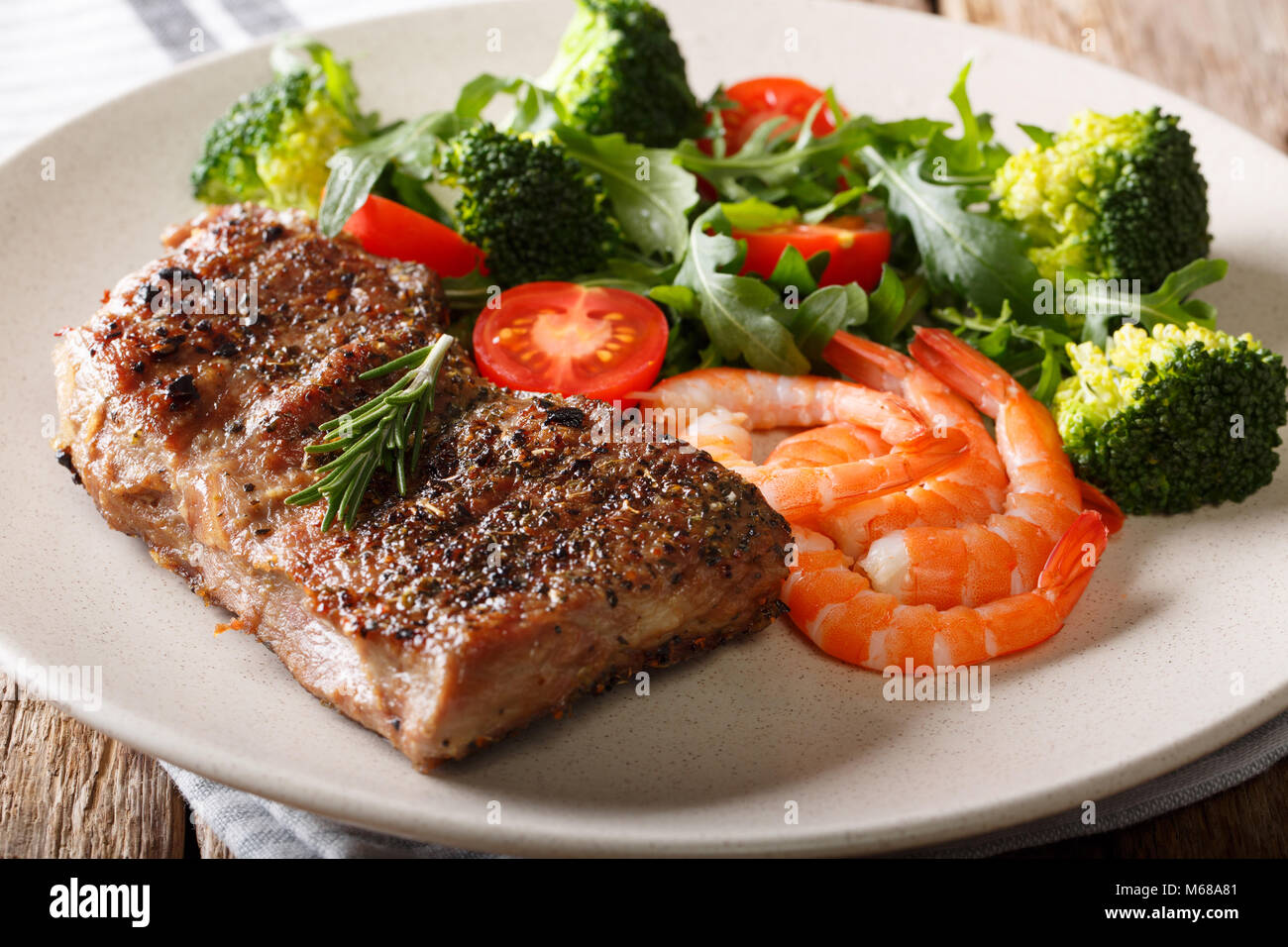 Terre et mer. Pavé de boeuf avec légumes frais et crevettes royale close-up sur une plaque sur une table. L'horizontale Banque D'Images