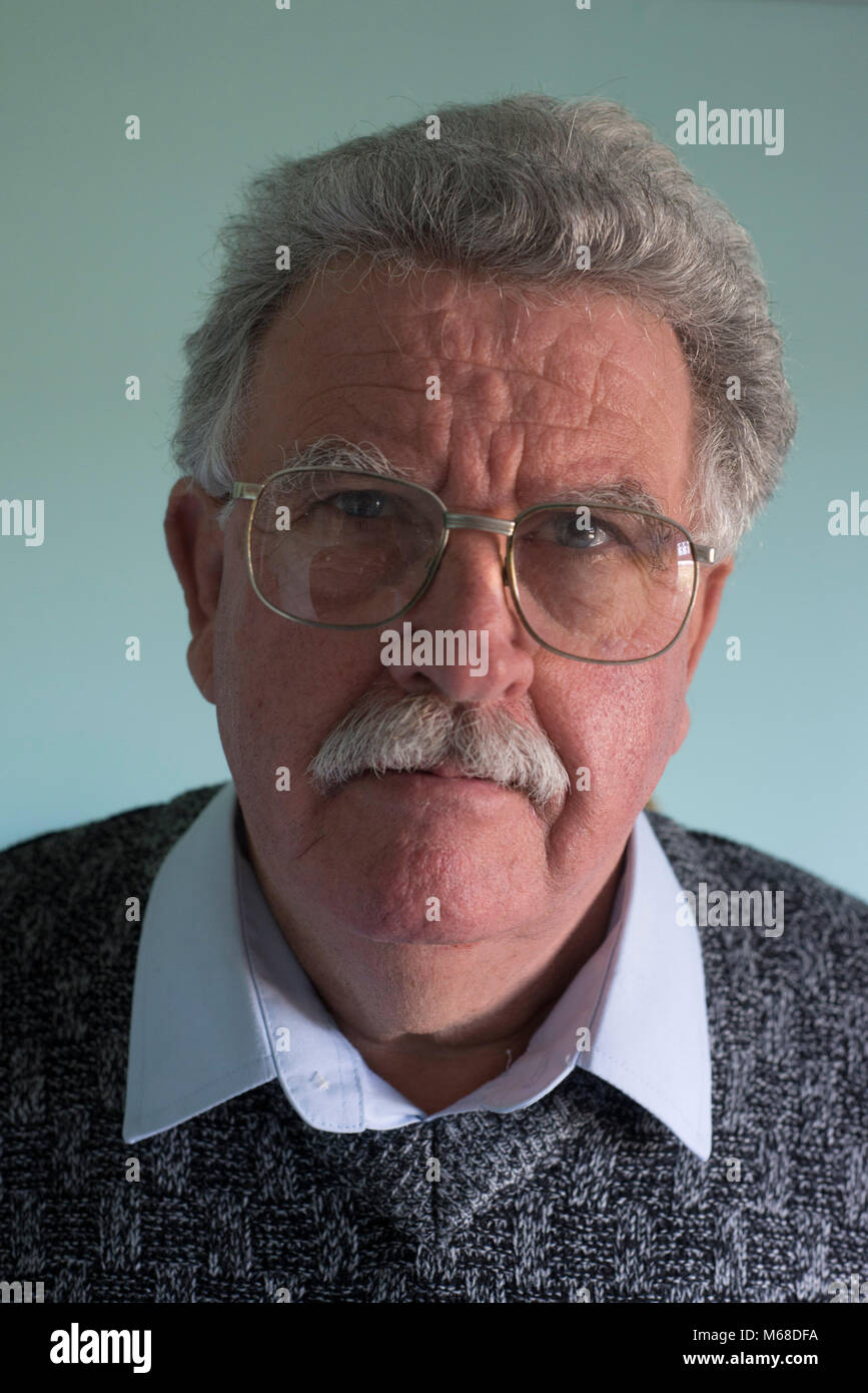 Head shot of a friendly accessible à la retraite ancien blanc homme avec une moustache et des lunettes Banque D'Images