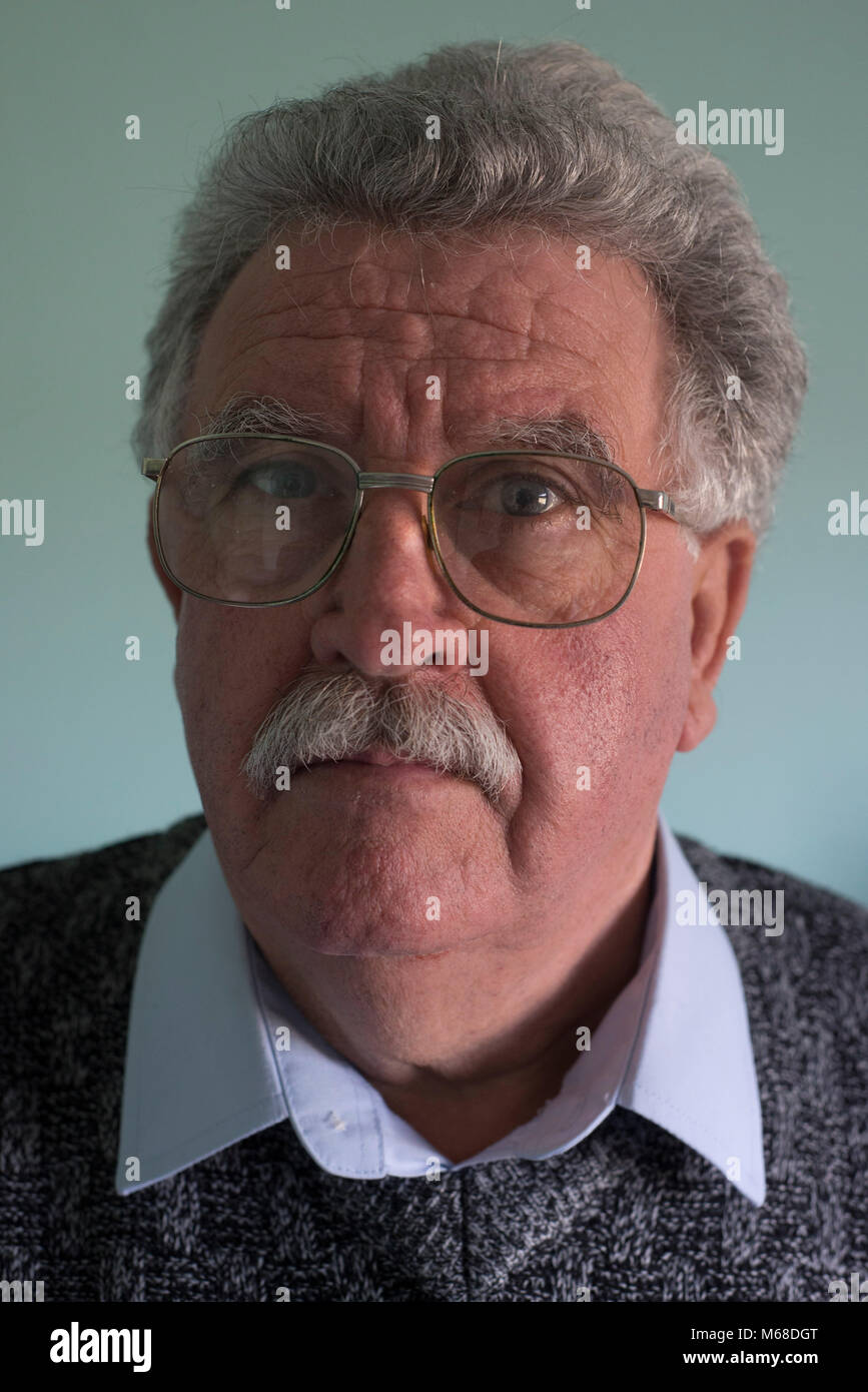 Head shot of a friendly accessible à la retraite ancien blanc homme avec une moustache et des lunettes Banque D'Images