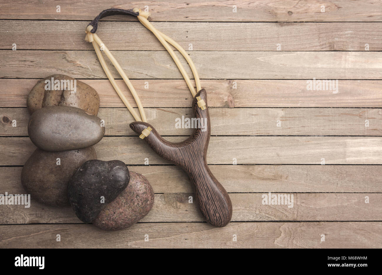 Représentant la lutte entre lance-pierres David et Goliath sur une table en bois Banque D'Images