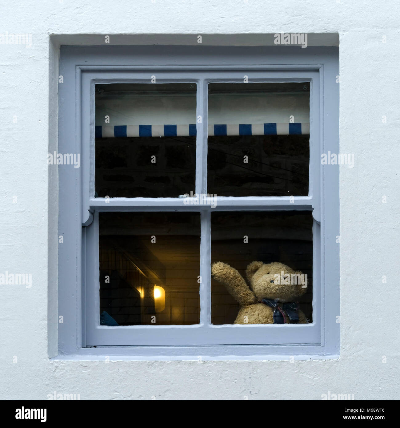 Joli ours en peluche qui agauge bonjour ou au revoir de la fenêtre de la maison suggérant l'auto-isolation ou la distanciation sociale pendant la pandémie du virus corona covid19 Banque D'Images