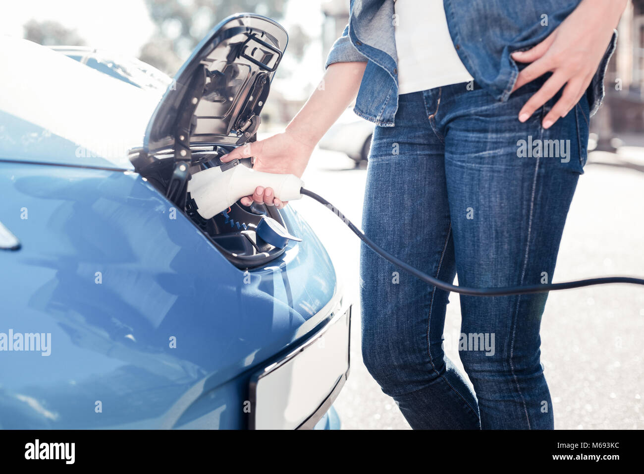 Une élégante femme étant près de voiture et de la recharger. Banque D'Images
