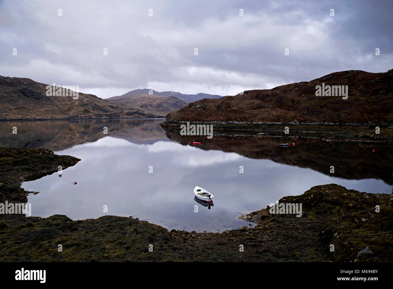Côte Nord 500 - blanc petit canot amarré sur le Loch Glendhu à marée basse sur un ton calme et jour nuageux, Kylesku, Sutherland, Highlands, Scotland UK Banque D'Images