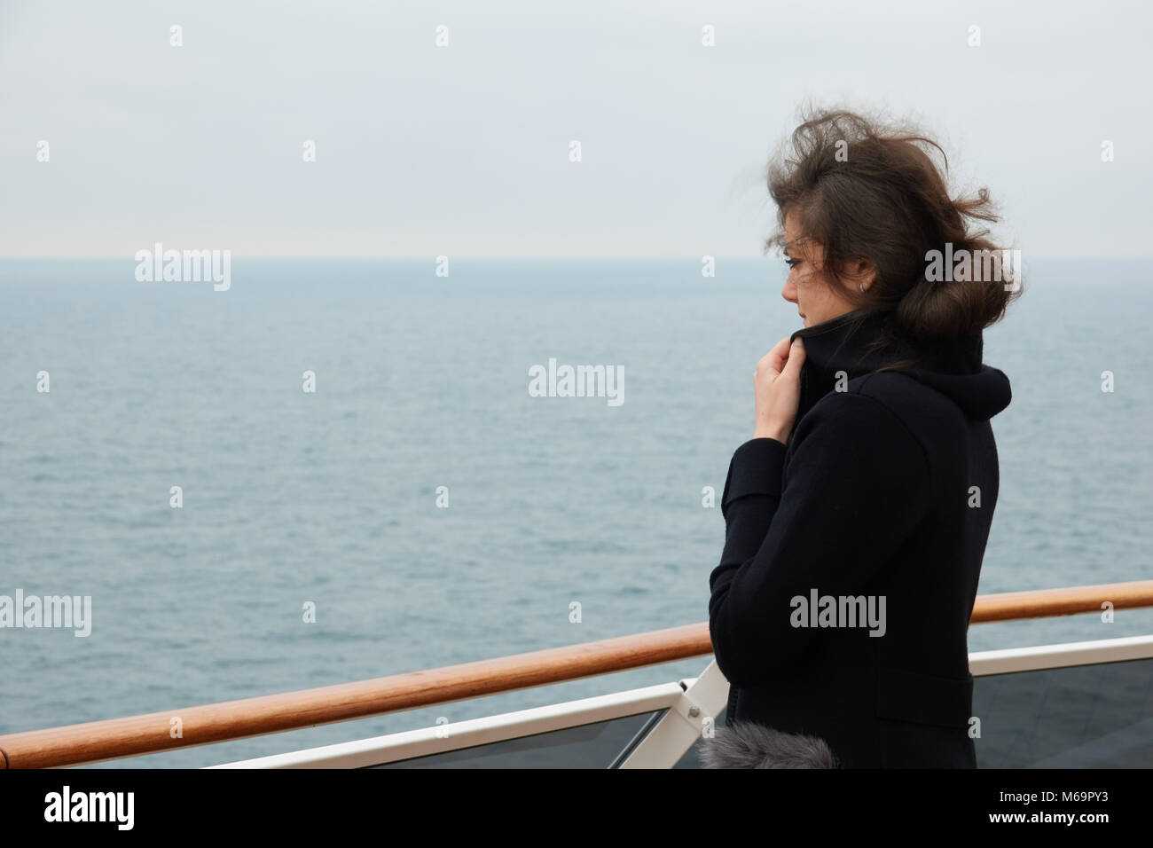 La fille se tient sur le pont d'un paquebot de croisière et s'ouvre sur l'océan dans le temps d'automne. Banque D'Images