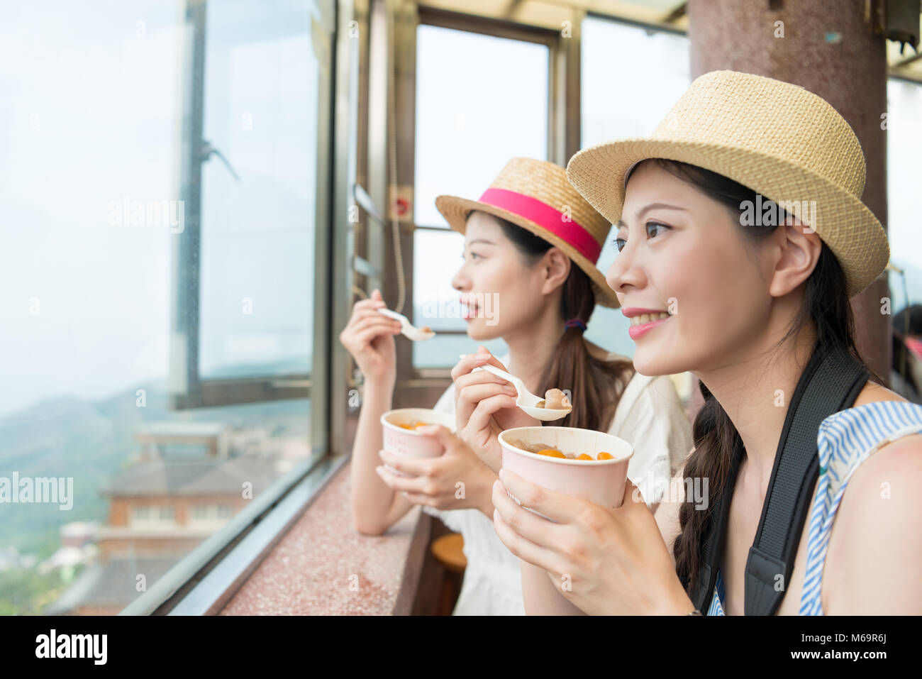 Filles asiatiques charme profitez de la vue du haut de la colline de Jiufen la ville de Taipei à Taiwan. Manger célèbre yam taro des balles pour grignoter. Banque D'Images