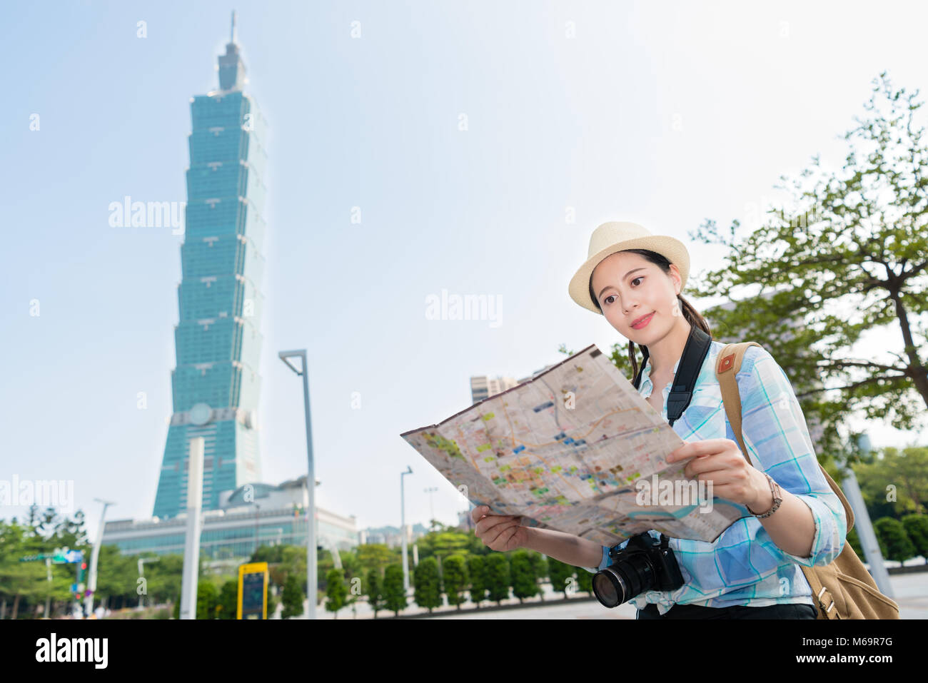 Smart Asian girl traveler jusqu'à la carte, une carte papier pour trouver son chemin dans cette magouille occupés plus haut bâtiment Taipei ville moderne. Elle va t Banque D'Images