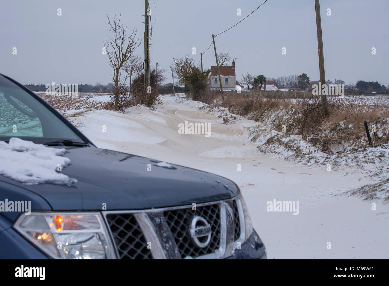 Happisburgh,Norfolk,UK. 1er mars 2018. Une route est bloquée sur toute sa longueur par des amoncellements de neige.Plusieurs cottages & maisons sont à gauche coupée par la neige, comme vu dans l'image. Ce n'est qu'une des nombreuses routes autour de la zone qui sont fermées par la neige ou par la police pour la sécurité publique. Une Nissan 4x4 est garé en face de la route bloquée. Crédit : Paul Lilley/Digitalshot/Alamy Live News Banque D'Images