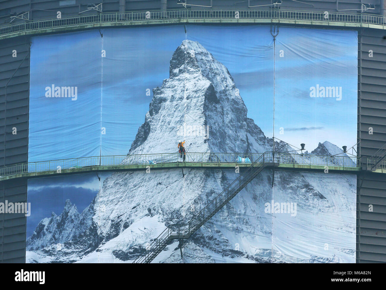 02 mars 2018, l'Allemagne, l'Oberhausen : un grimpeur industrielle met en place d'un 1400 m² grand poster pour l'exposition "der Berg ruft" (lit. Les appels de montagne) à l'gazomètre d'Oberhausen. L'exposition a lieu du 16 mars au 31 décembre 2018 et affiche une sculpture monumentale du Cervin à l'espace aérien de 100 mètres de haut du gazomètre. Photo : Roland Weihrauch/dpa Banque D'Images