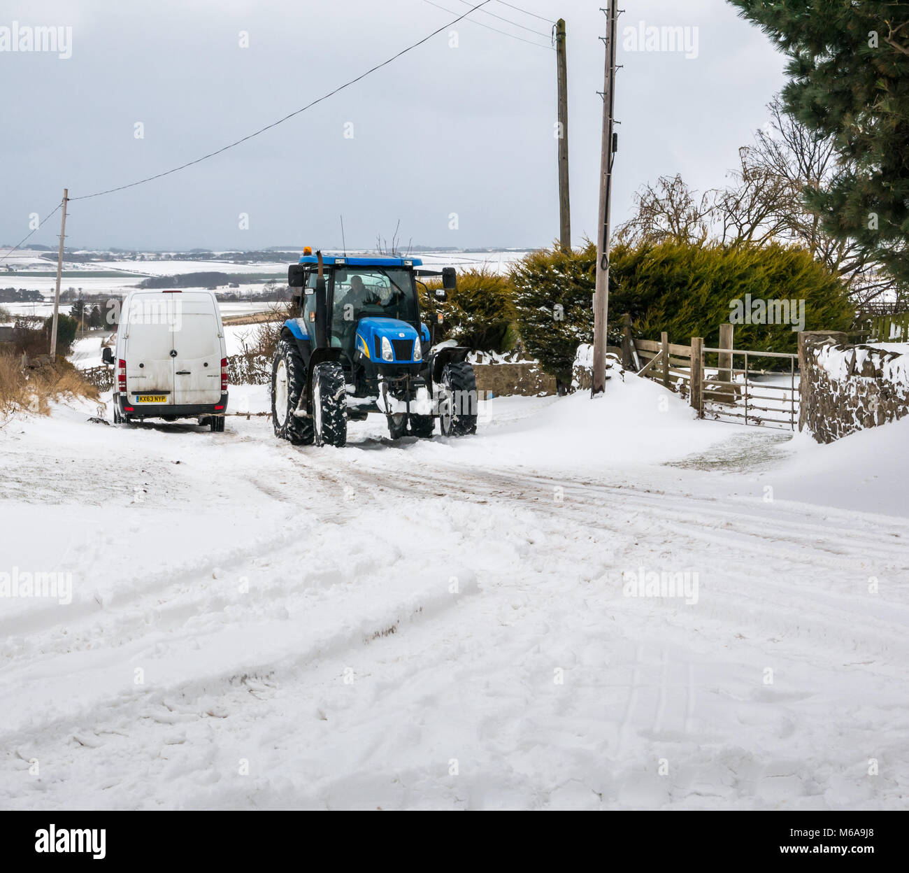 East Lothian, Ecosse, Royaume-Uni, 2 mars 2018. Météo France : la "bête de l'Est arctique' agrippe le paysage rural. Les amoncellements de neige sur certaines sections de la route sont plusieurs pieds de haut dans les lieux,. Un tracteur tire une camionnette blanche Retour en haut de la colline, après qu'il est resté coincé Banque D'Images