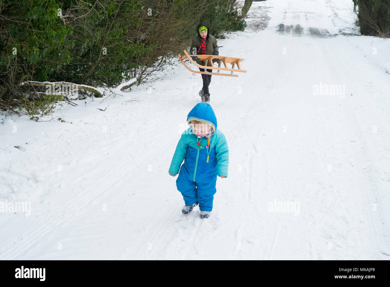 Garçon de huit ans et son frère âgé de 18 mois. La luge ou de la luge dans la neige , Medstead, Alton, Hampshire, Angleterre, Royaume-Uni. Banque D'Images