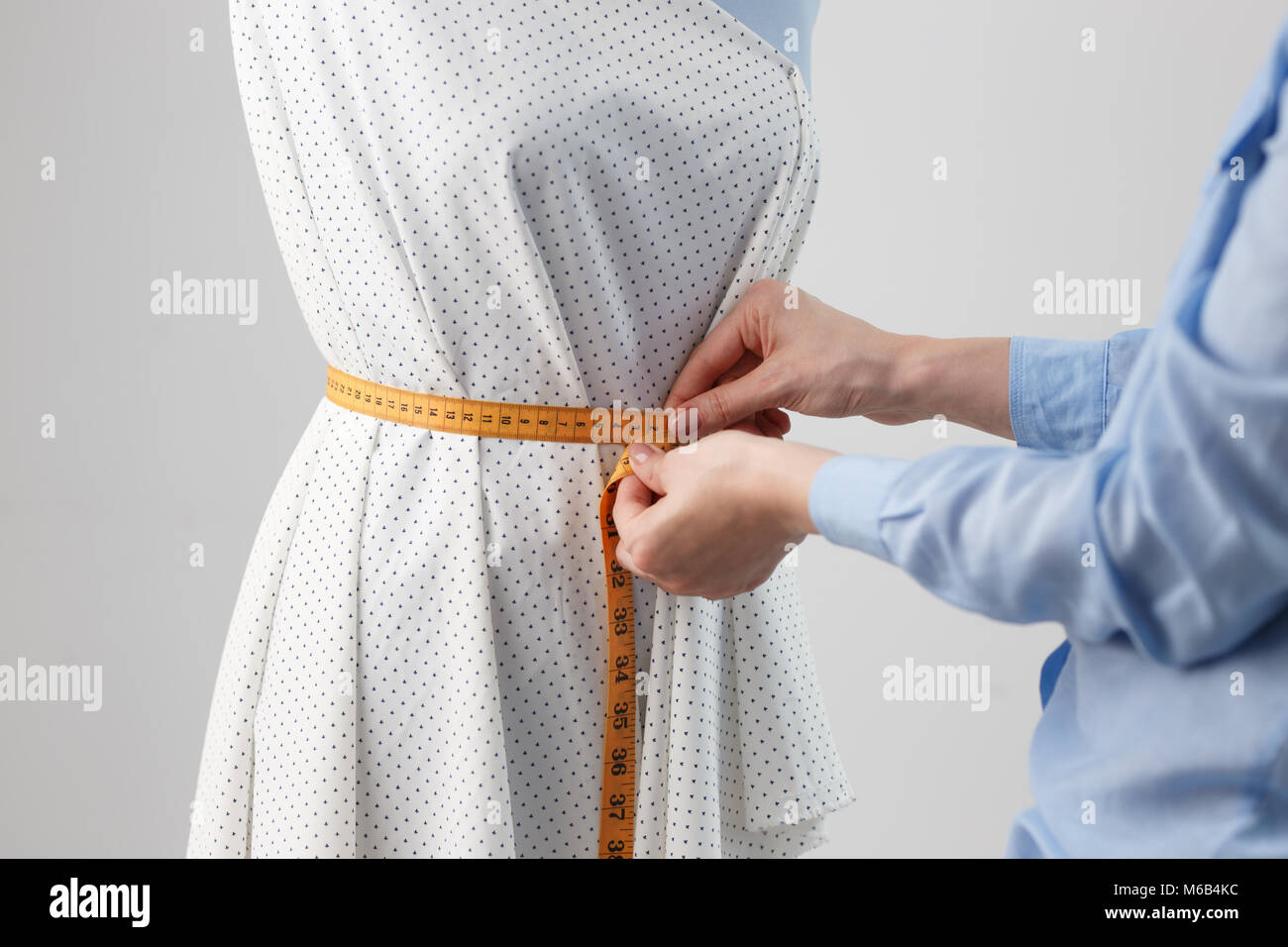 Femme couturière travaillant sur nouveau modèle couture robe sur mannequin en studio Banque D'Images