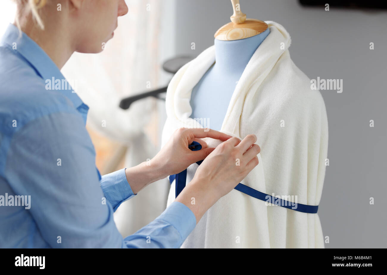 Femme couturière travaillant sur nouveau modèle couture robe sur mannequin en studio Banque D'Images