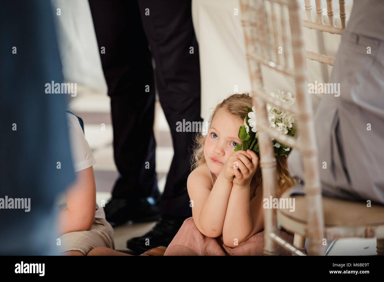 Petite fille est assise sur la piste d'un tableau à un mariage. Elle regarde la mariée et le marié partagent leur première danse. Banque D'Images