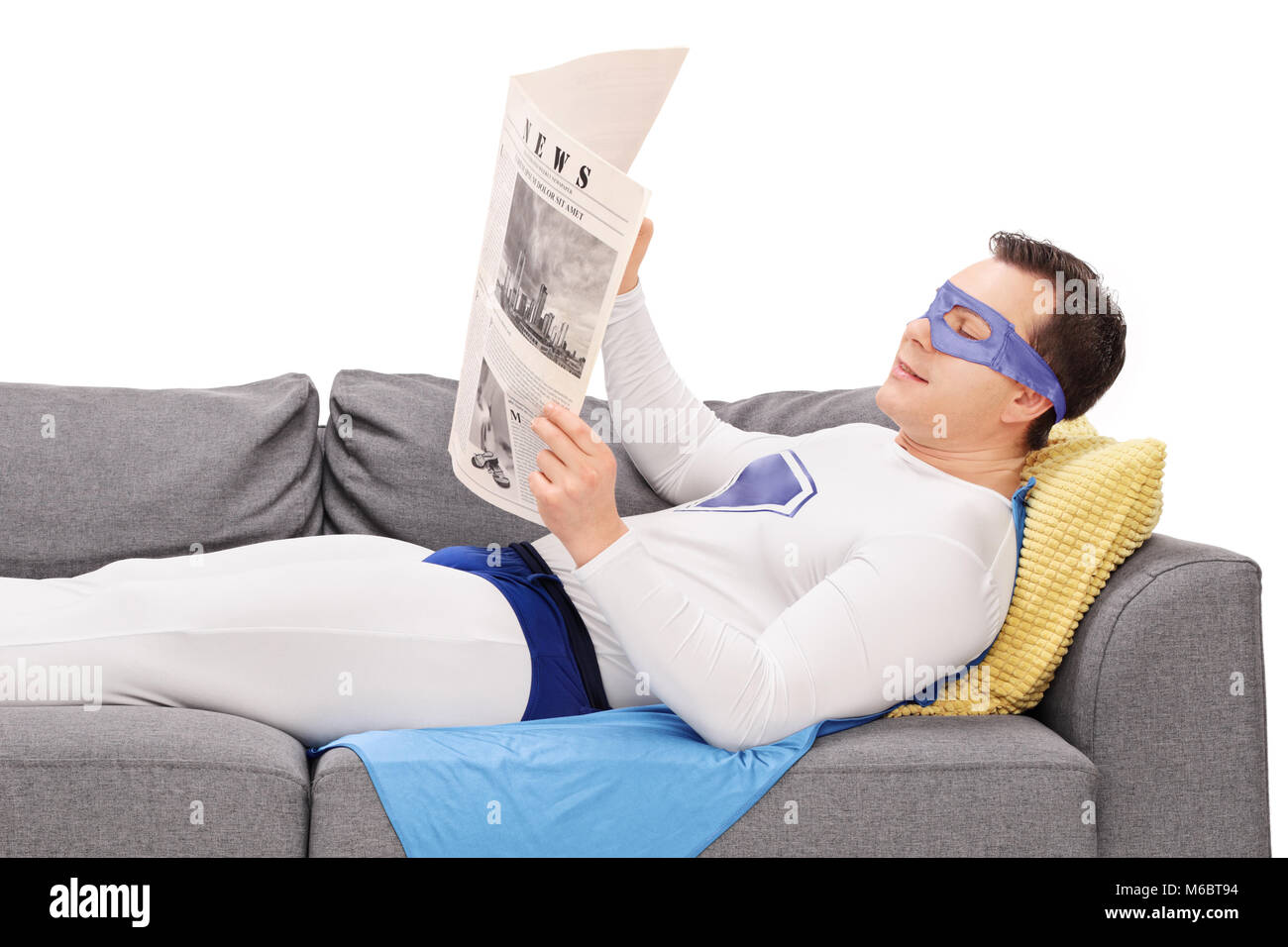 Super Héros allongé sur un canapé et lit un journal isoalted sur fond blanc Banque D'Images