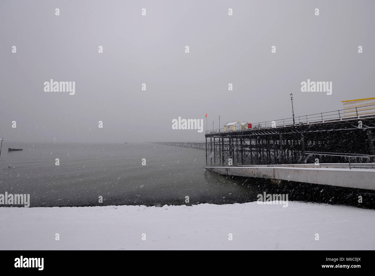 Southend Pier couvert de neige et plage avec nuages de neige. Neige. Cabanes colorées. Jambes en fer. Bateau Banque D'Images