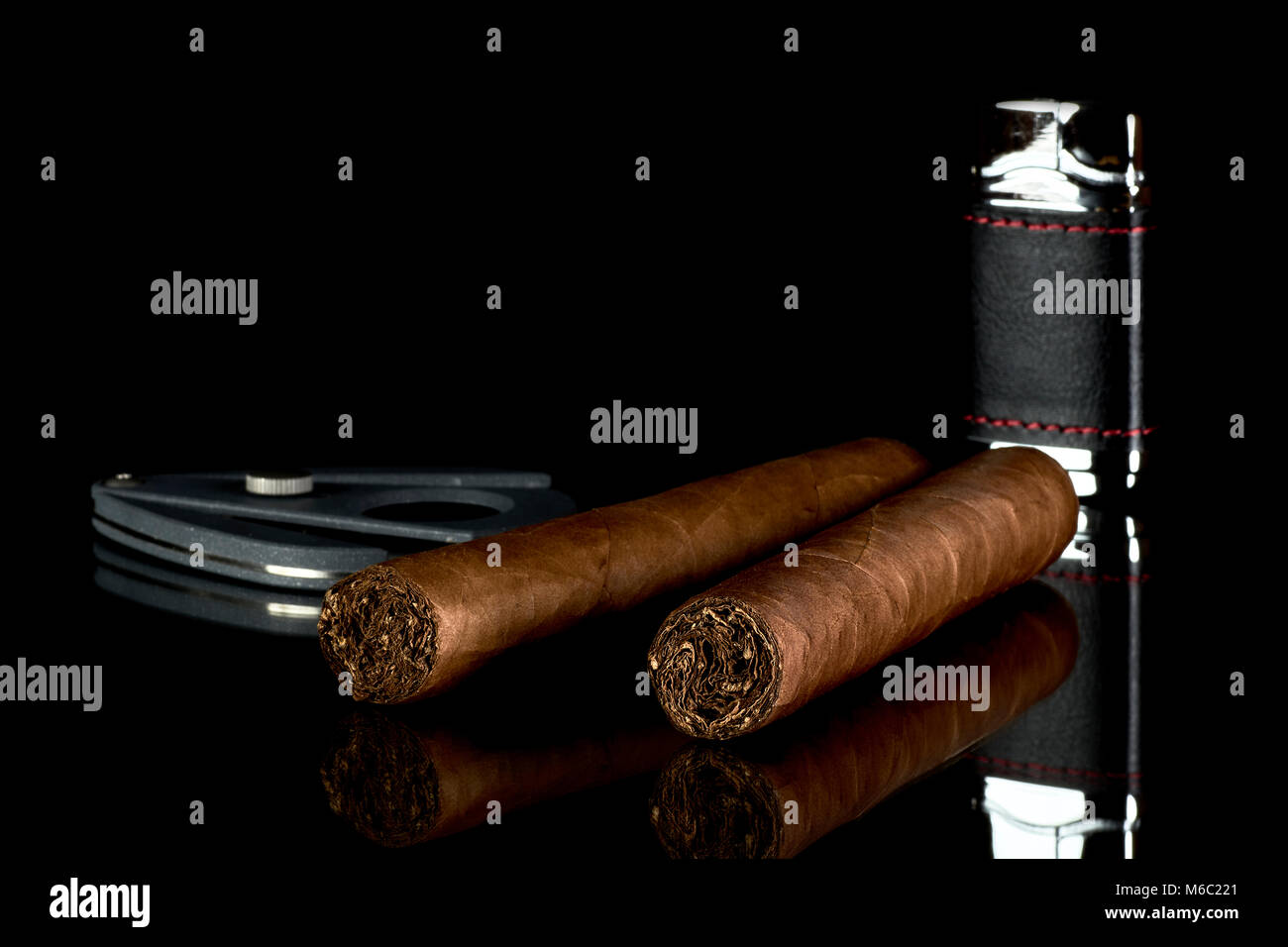 Deux cigares cubains avec un briquet et un couteau sur un verre avec un fond noir Banque D'Images