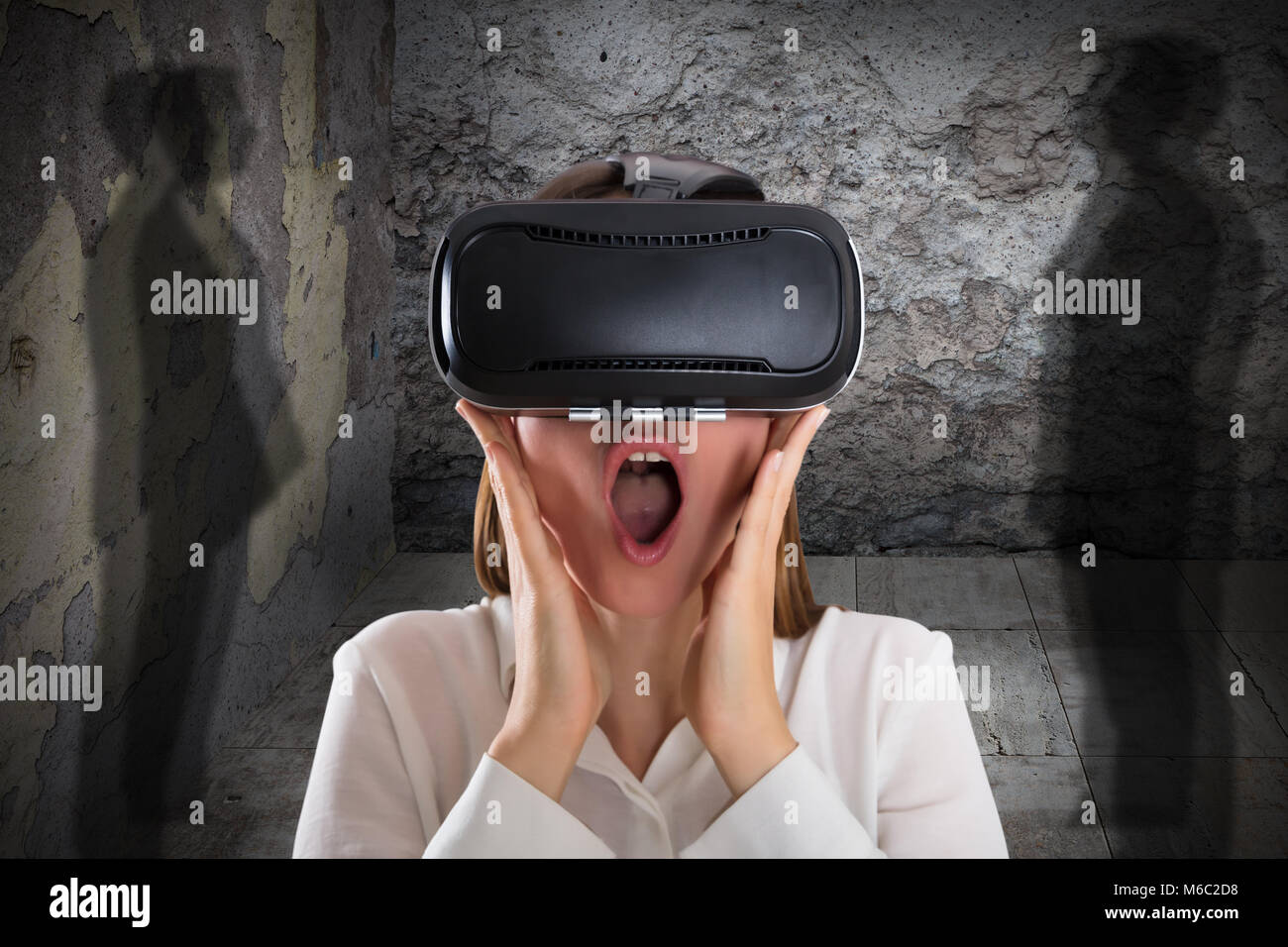 Close-up of a peur Femme portant des lunettes de réalité virtuelle avec bouche ouverte près de l'ombre Banque D'Images