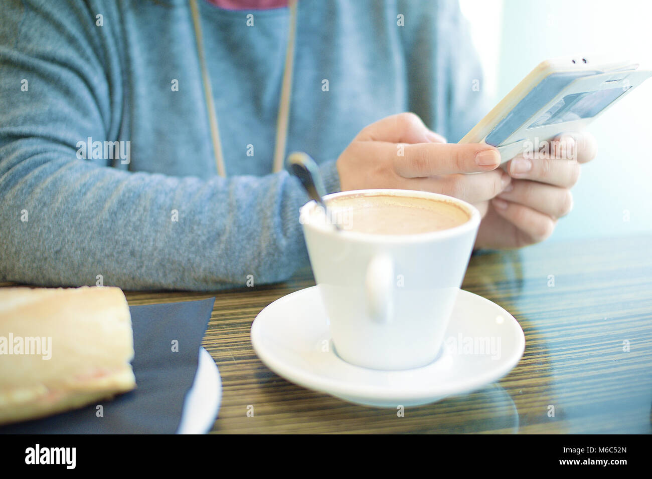 Jeune femme prenant le café à côté d'une fenêtre à l'aide d'un mobile. Copie vide de l'espace pour l'éditeur de texte. Banque D'Images