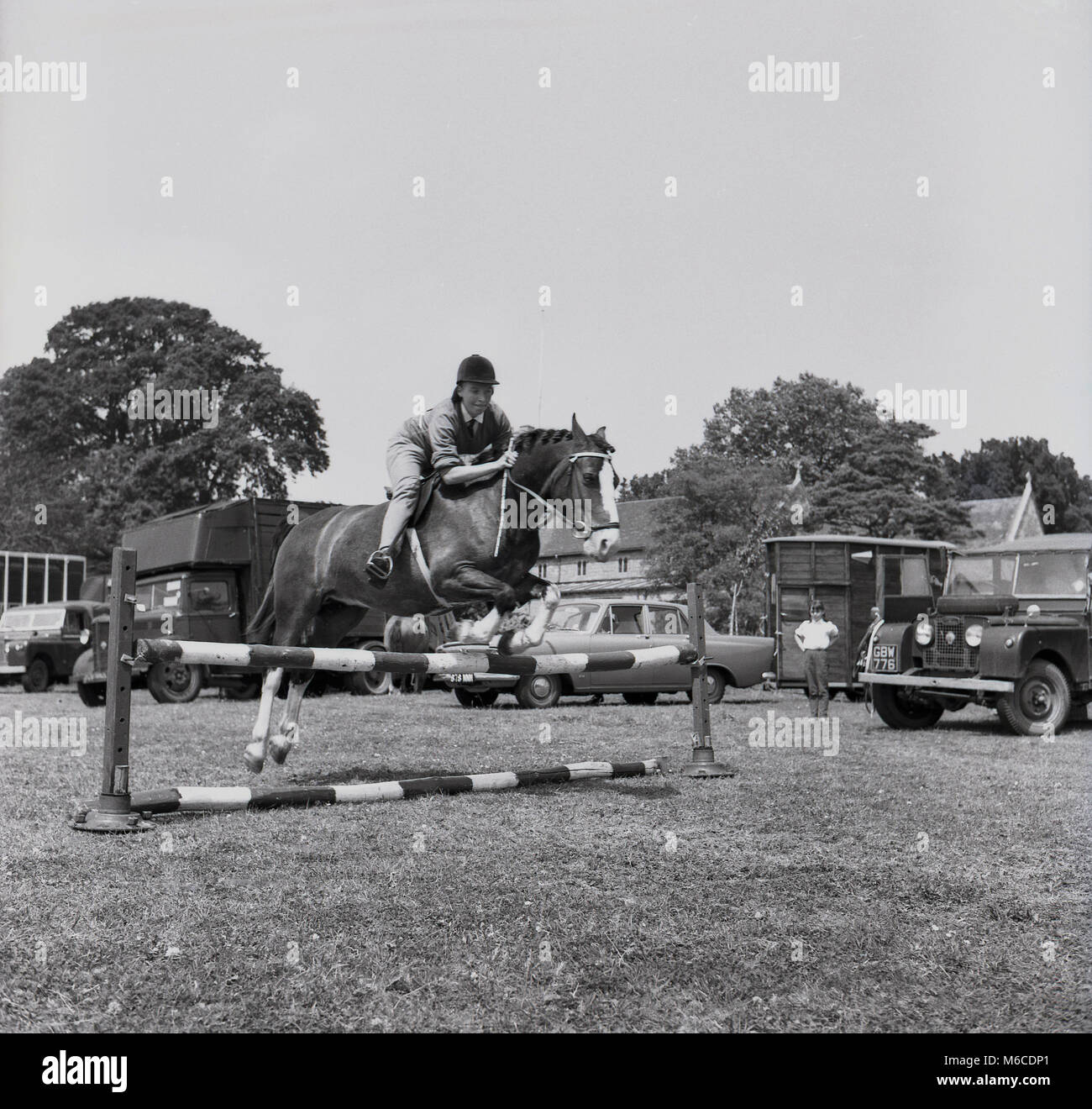 Années 1960, historiques, femme de saut sur un cheval montrant une bonne technique sautant par dessus une clôture ou d'un obstacle dans la pratique, England, UK. Banque D'Images