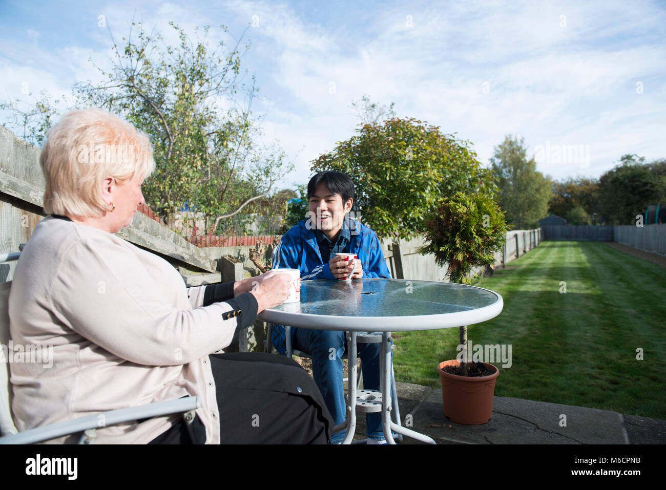 Un logement étudiant avec son siège d'accueil des étudiants internationaux dans le jardin de boire du thé et parler. Banque D'Images