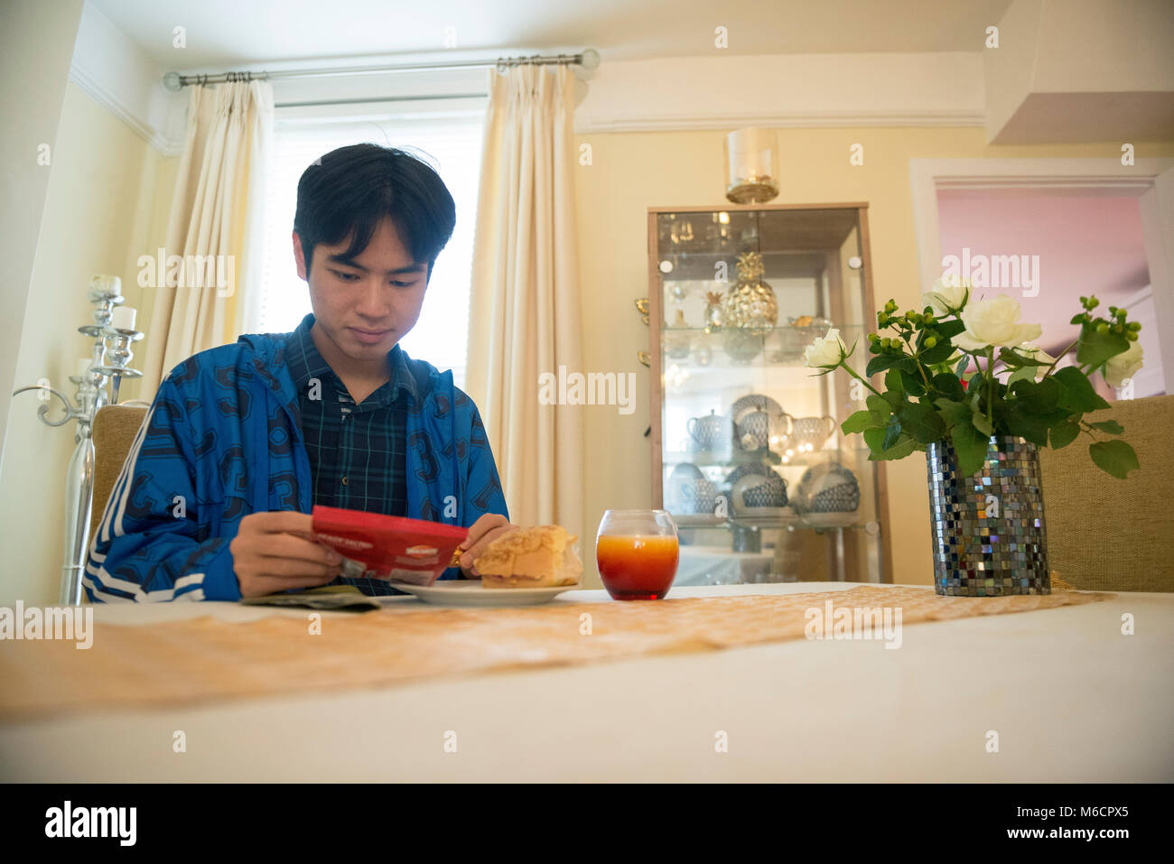 Un jeune étudiant international outre-mer asiatique obtient et prépare son déjeuner dans la cuisine de sa famille d'accueil home Banque D'Images