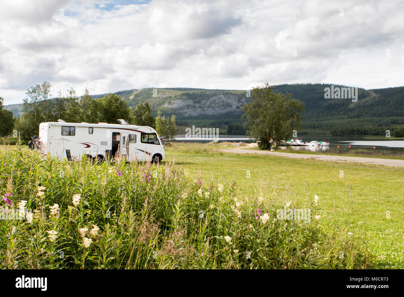 Grand camping stationné sur l'herbe verte près d'un lac en Scandinavie. Banque D'Images