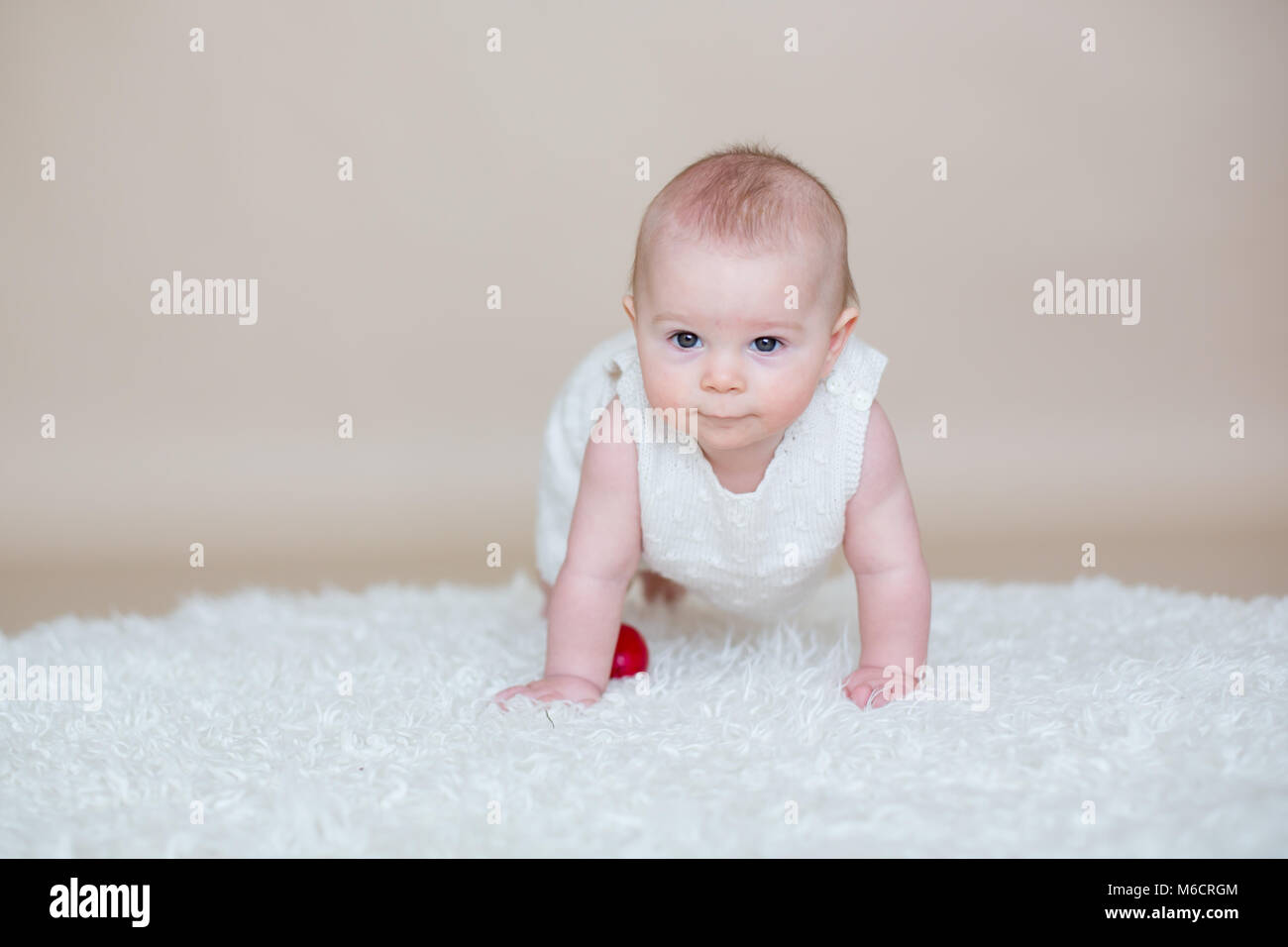 Cute little toddler baby boy, jouant avec les oeufs de Pâques colorés et peu de canards décoratifs, isolé tourné, fond beige Banque D'Images