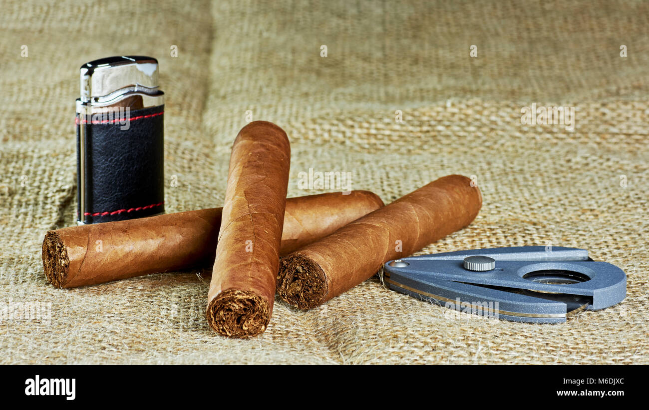 Trois cigares cubains avec un briquet et un couteau sur un fond de jute Banque D'Images