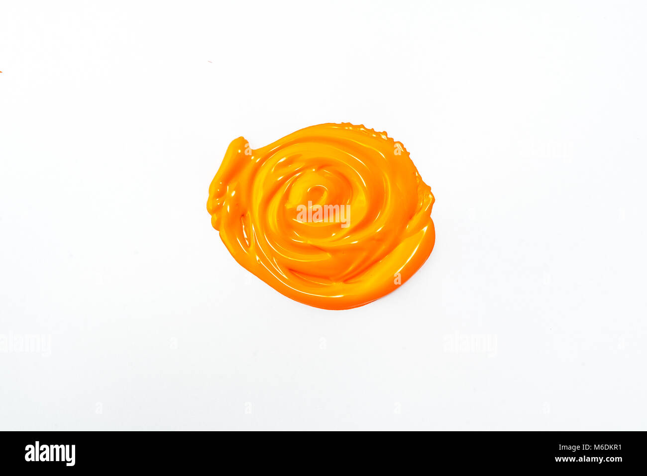 Une goutte de peinture acrylique couleur orange sur une surface blanche Banque D'Images