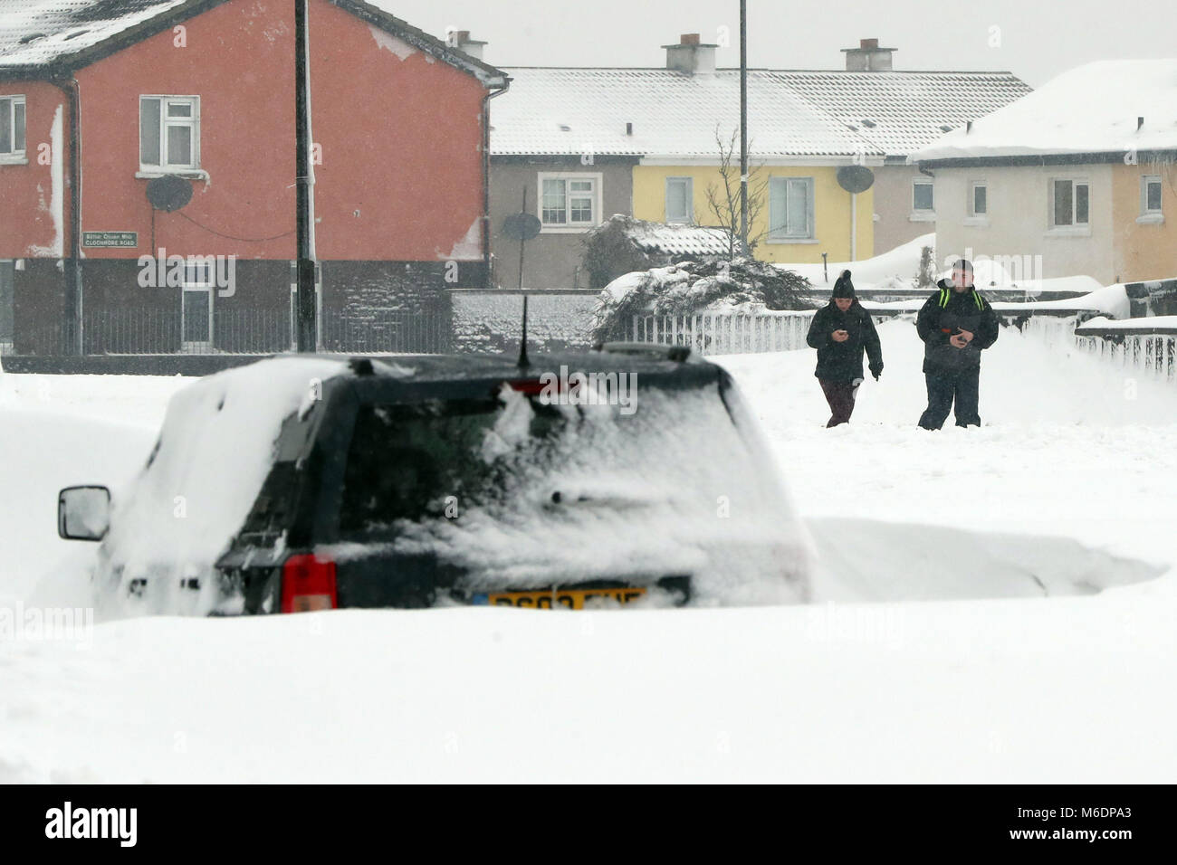 Les membres du public à pied regarder un feu voiture endommagée à Jobstown Projects, Tallaght, Dublin que neuf personnes ont été arrêtées après un supermarché a été attaqué à Dublin pendant un blizzard. Banque D'Images