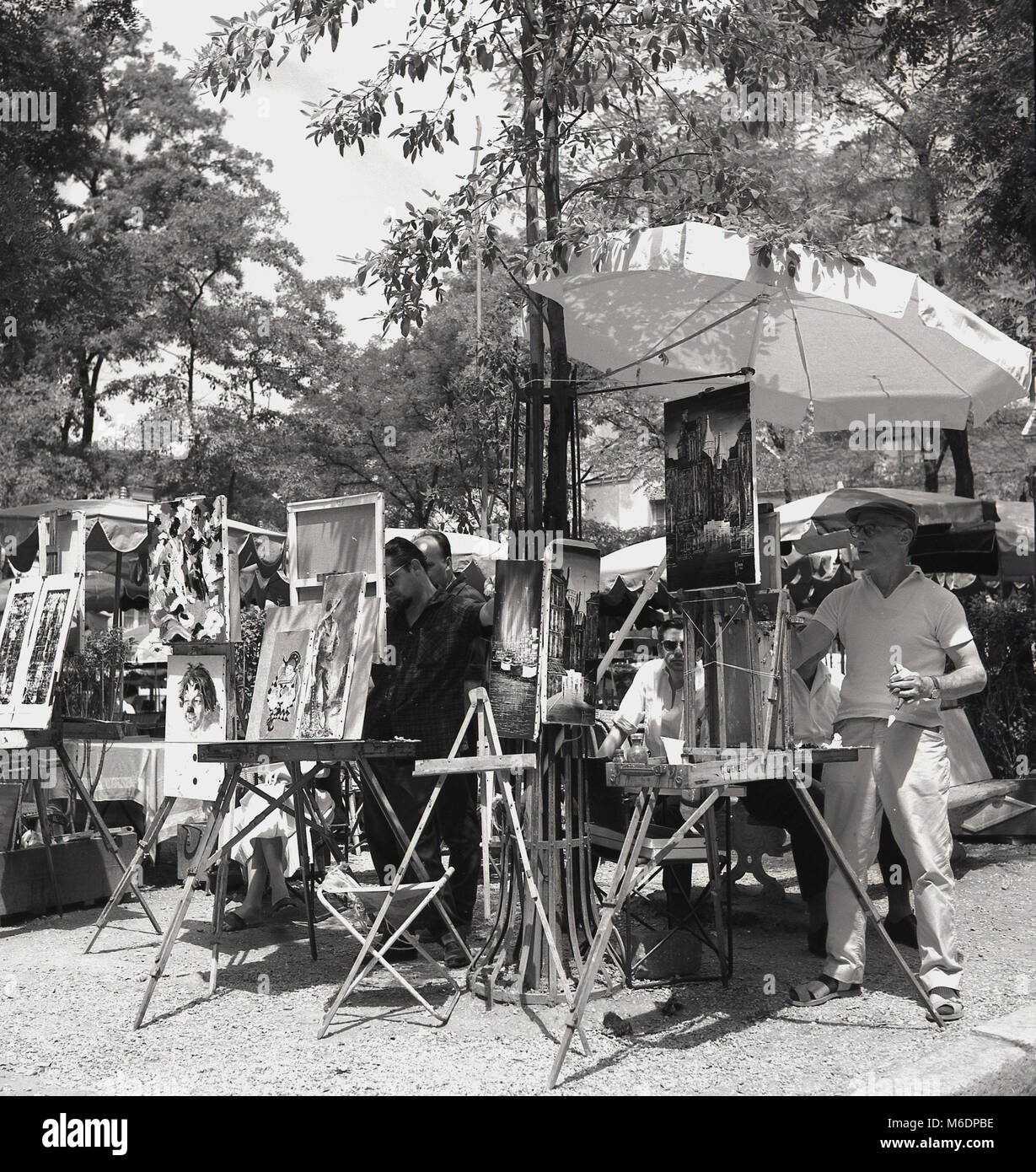 Années 1950, Paris, France, l'heure d'été et les artistes de rue parisienne travaillant sur leurs peintures à l'ombre sur la place de Montmartre. Banque D'Images