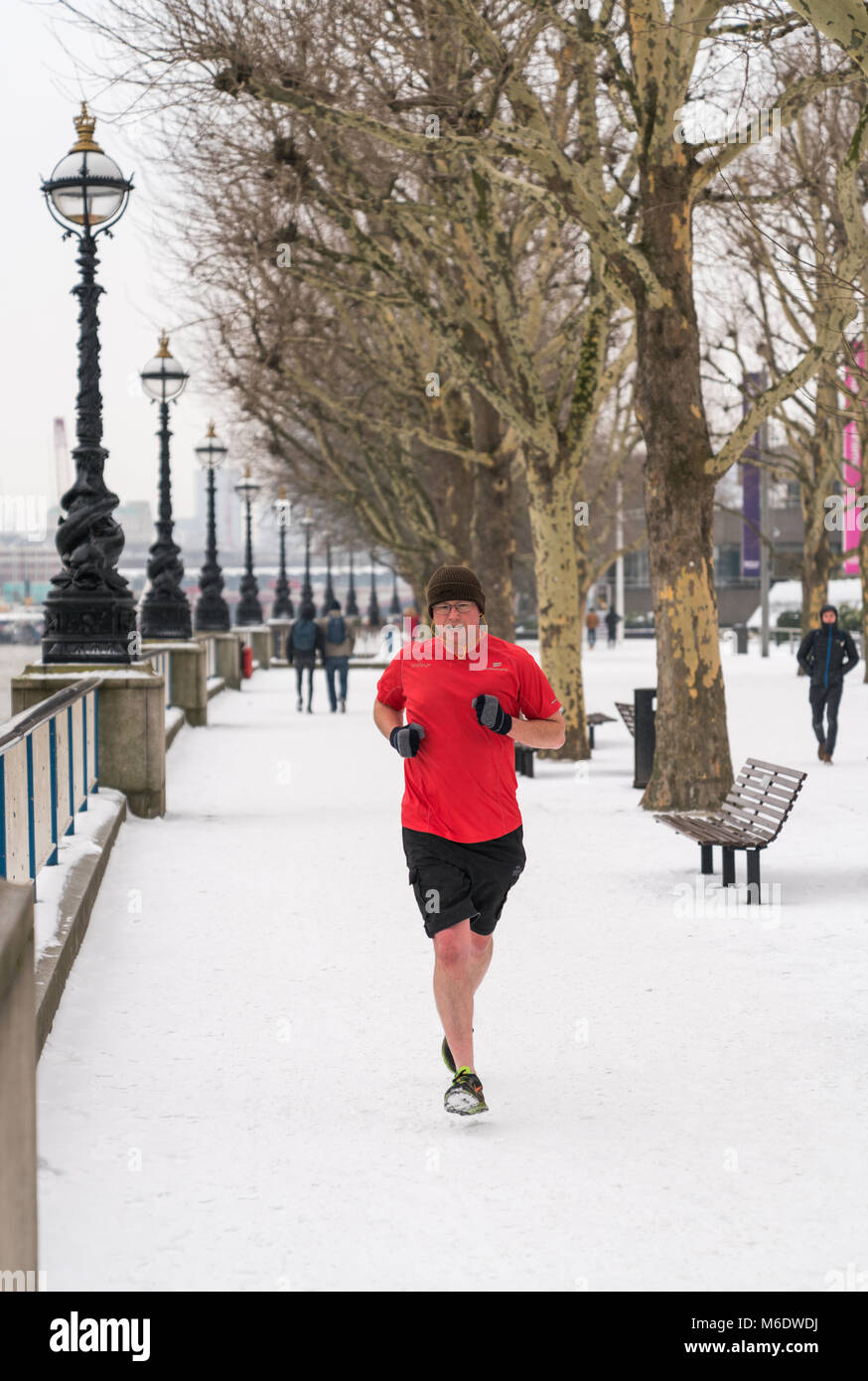 01 mars 2018 - Londres, Angleterre. Un homme portant des shorts, courir sur la neige, en bas du talus par temps froid. Banque D'Images