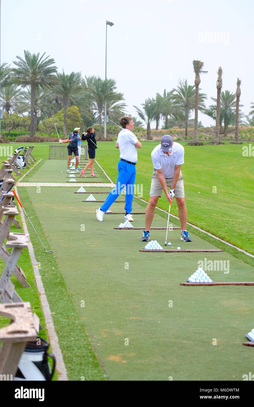Groupe de joueurs de golf train / pratiquant à Saadiyat Beach Golf Course, Abu Dhabi ÉMIRATS ARABES UNIS. Banque D'Images